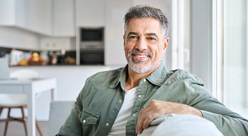 Senior man smiling while sitting on couch