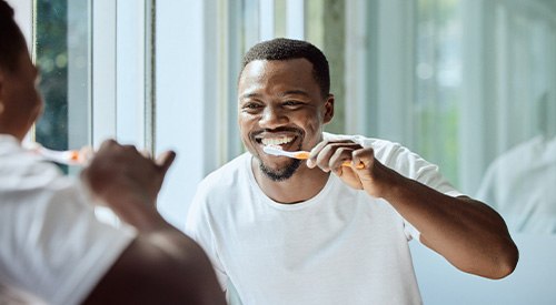 Man smiling while brushing his teeth