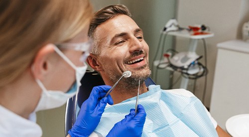 Man in dental chair smiling before exam
