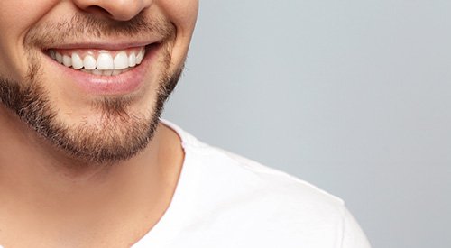 Nose-to-shoulder view of man in white t-shirt smiling