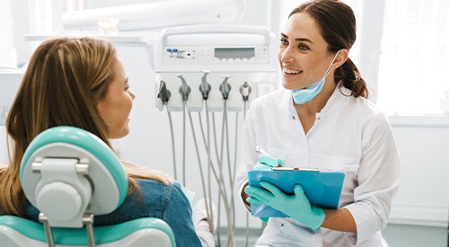 Dentist smiling at patient while taking notes on clipboard