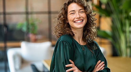 Woman in green shirt smiling with arms folded