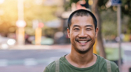 Man with mustache and beard walking down the street and smiling