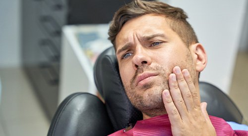 Patient in treatment chair struggling with toothache