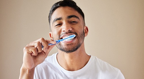 Man smiling while brushing his teeth