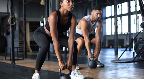 Man and woman lifting weights in gym